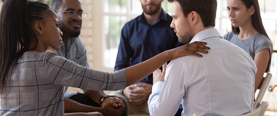 AfricanPsychologistSupportingMaleRehabSessionParticipantPutHandOn | Evok Advertising Effective Healthcare Marketing Beyond the Stigma